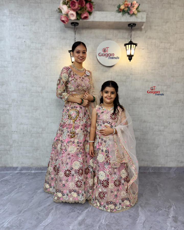 Two women in matching floral outfits standing in front of a branded wall.